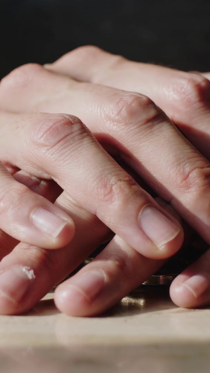 Vertical video: Placing adult hands pressing slightly on light tabletop, covering coin and residue