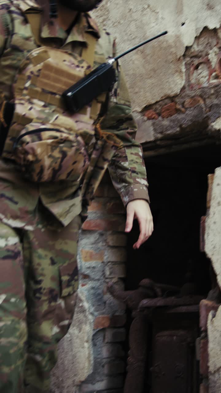 Soldier Looks Through The Destroyed Door Of An Old House