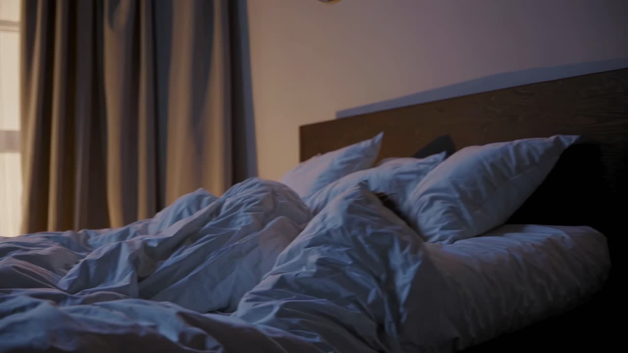 A cozy bedroom scene with rumpled bedding, captured from a low angle