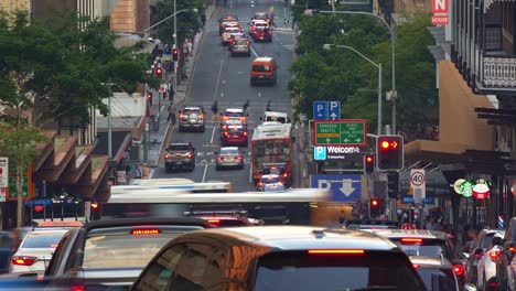 zoomed time-lapse shot of rush hour traffic on edward street in brisbane central business district with pedestrians crossing, buses and cars driving and running in all directions.