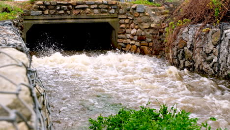 rainwater gushing out of storm drain on coastline, static real time