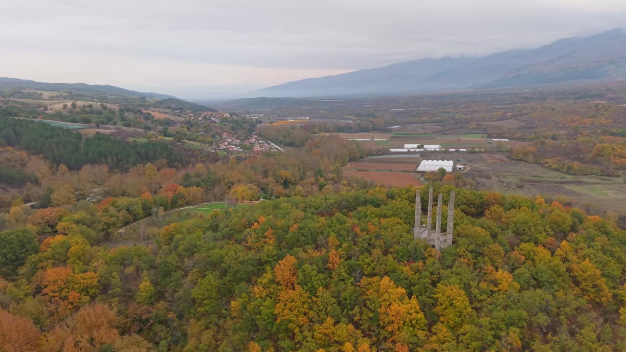 Drone captures an aerial view of Samuil's Fortress on a hill in Bulgaria, surrounded by trees on a rainy autumn day with misty and moody atmosphere