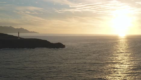 Panoramadrohnenaufnahme-Eines-Leuchtturms-Zur-Goldenen-Stunde-Mit-Meer-Und-Sonne