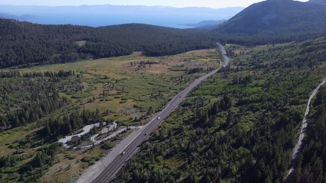 toma aérea después de un automóvil que conduce por la carretera para revelar el lago tahoe y las montañas circundantes
