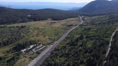 Aerial-shot-following-a-car-driving-down-the-road-to-reveal-Lake-Tahoe-and-the-surrounding-mountains