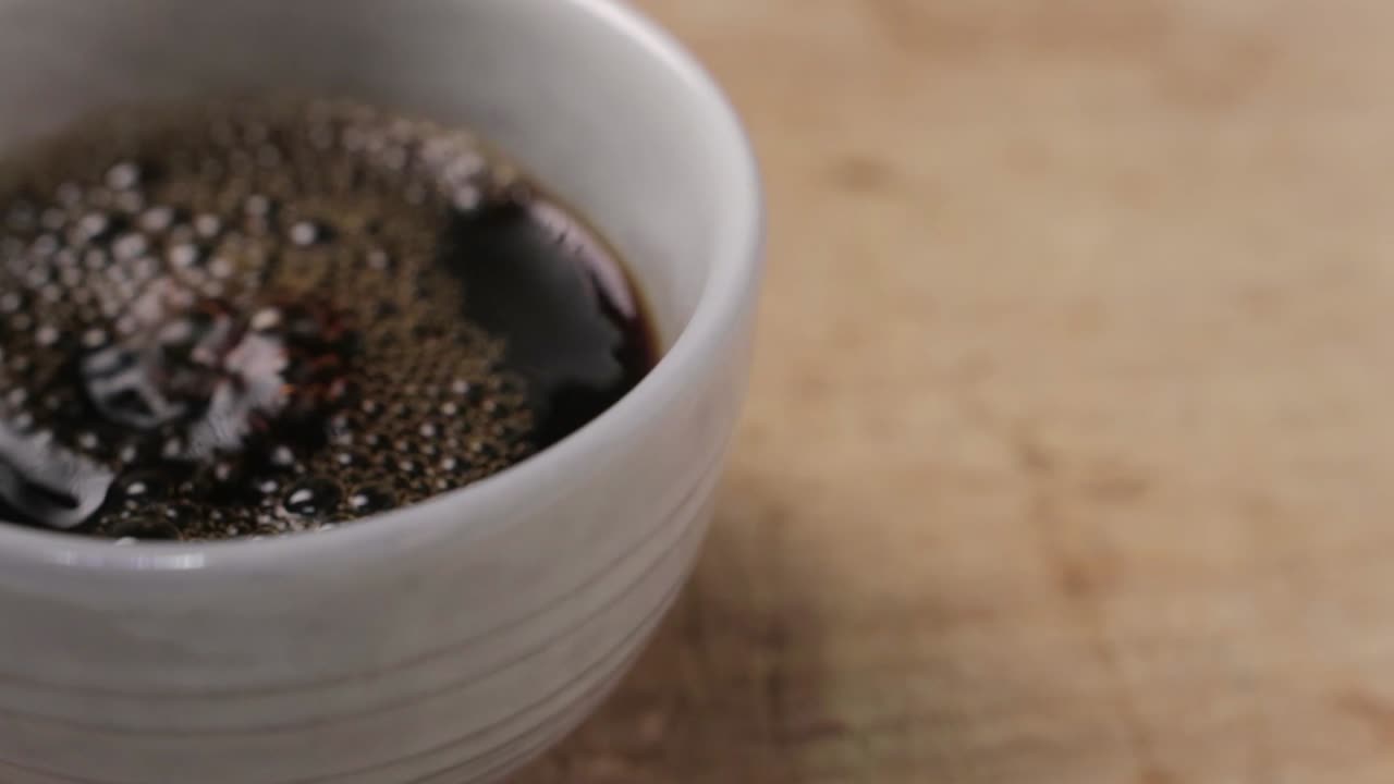 Pouring Cup of Coffee followed by Hand grabbing the Cup Leaving the Frame. With wood background and space for copy