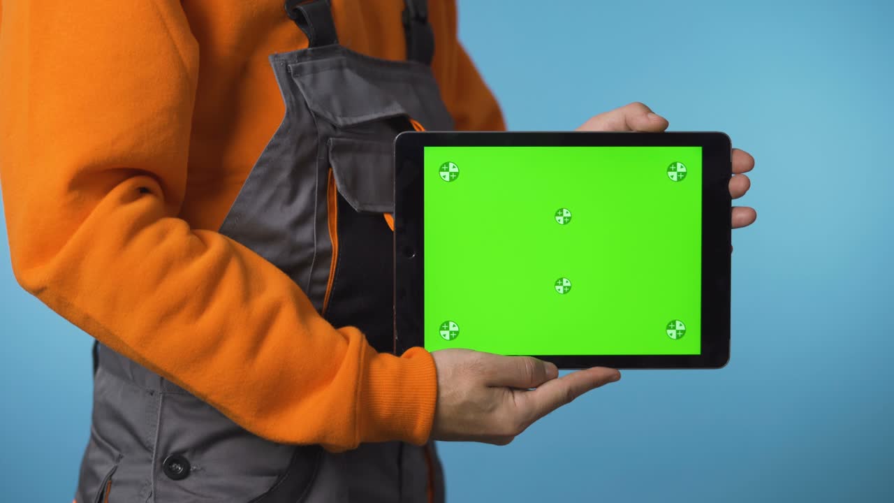 una foto cercana de un hombre de todo derecho sosteniendo una tableta con pantalla verde