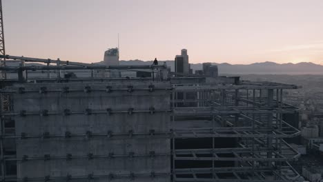 a young adult male stands on a skyscraper in downtown los angeles at sunrise