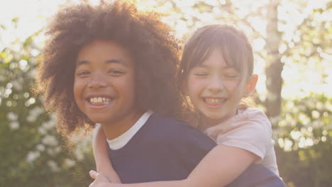 portrait of smiling boy giving girl piggyback outdoors in garden