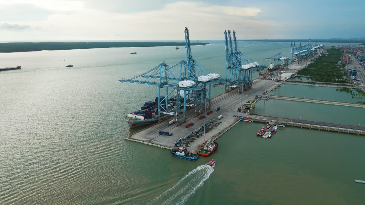 Zoom-out orbit drone shot of a container ship loading cargo at Klang Port during the day in the state of Selangor, Malaysia