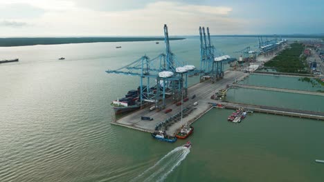 zoom-out orbit drone shot of a container ship loading cargo at klang port during the day in the state of selangor, malaysia