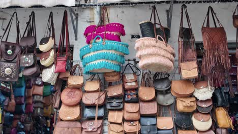 colorful handmade leather and woven bags hanging in a marketplace in morocco