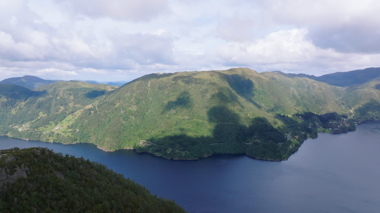 Drone footage flying towards Osterøy in Western Norway, revealing a scenic fjord with blue waters, steep mountains, and lush valleys in a tranquil Nordic landscape