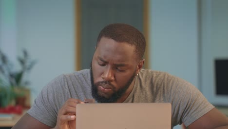 African-man-eating-chocolate-cookie-at-workplace.-Portrait-of-guy-eating-cookie