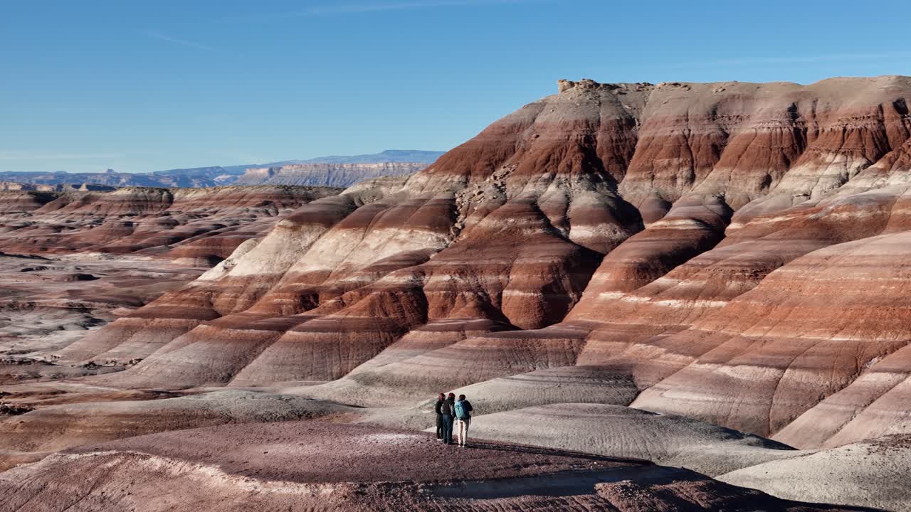 Ripresa con drone orbitante di tre persone nel paesaggio delle Bentonite Hills, Utah, USA