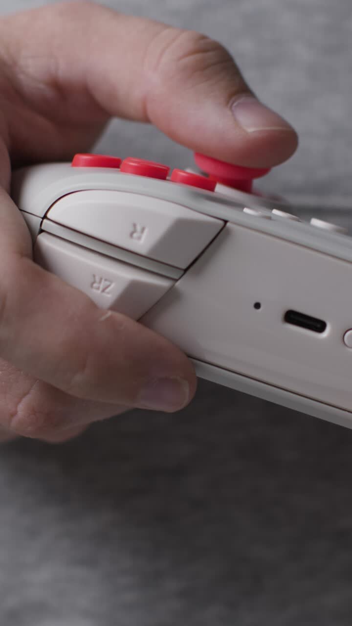 Video verticale: Primo piano frontale, mani di un uomo che gioca con un controller di videogiochi, ripresa 1