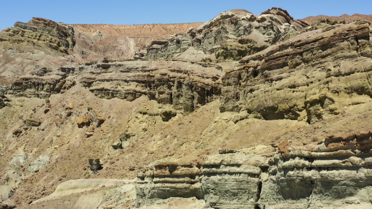 volando sobre las montañas y capas de tierra en un desierto para revelar un camino de tierra que serpentea a través del paisaje en la distancia