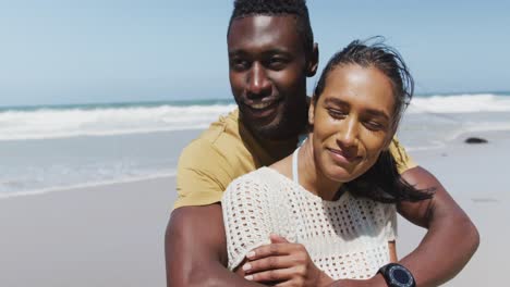 happy african american couple hugging and embracing each other at the beach