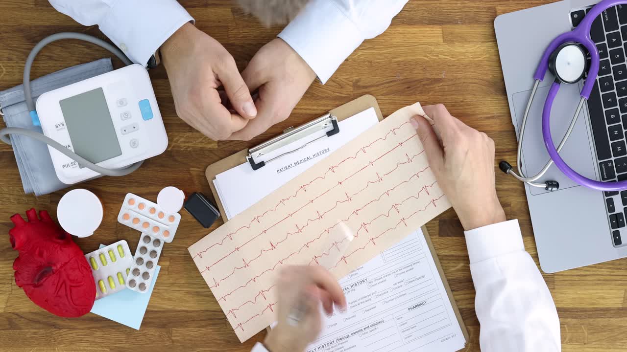 Doctors reviewing a patient's medical history, ECG results, and medical equipment