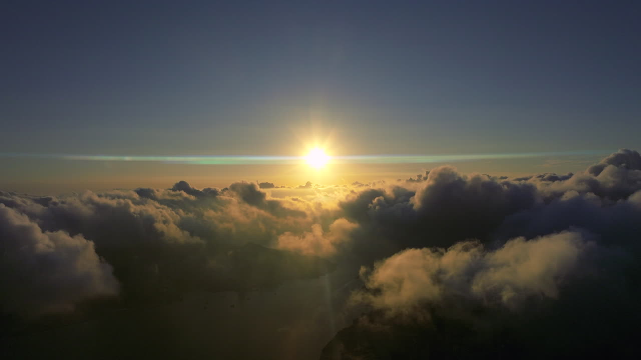 toma aérea de un dron del amanecer dorado con un destello de lente anamórfico sobre el paisaje nublado por la mañana