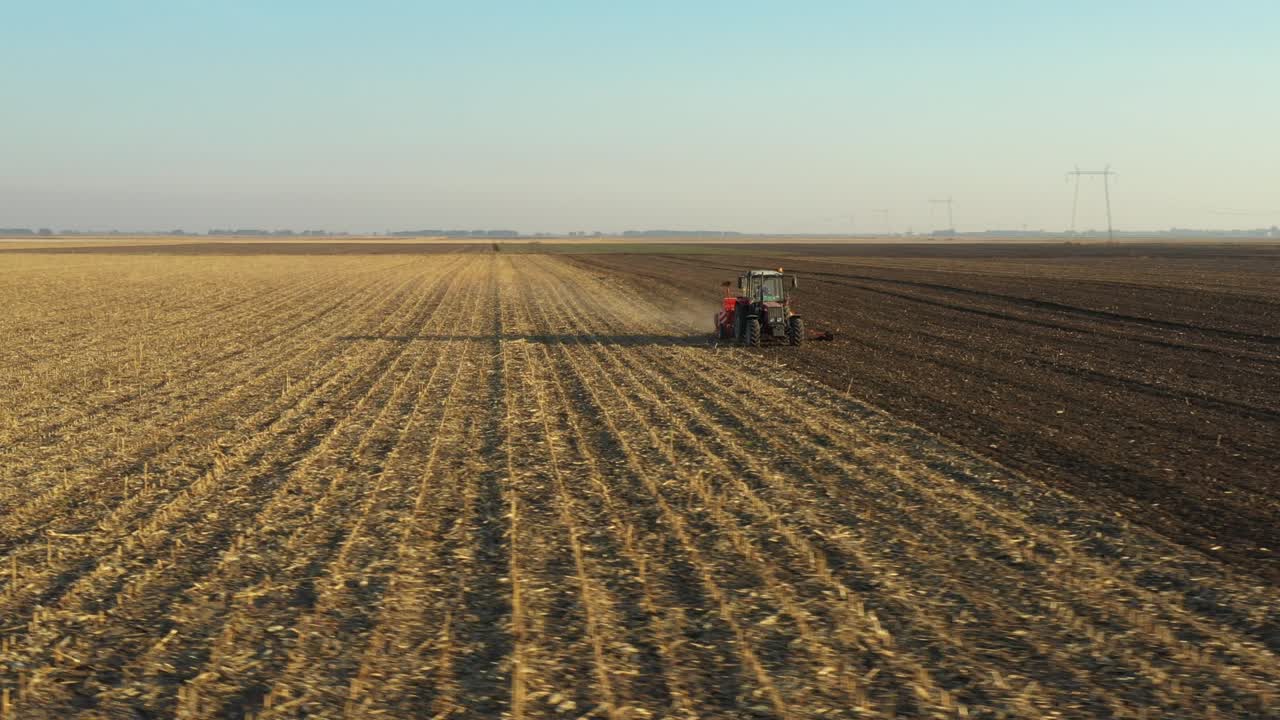 movimiento en órbita de dolly en vista aérea superior del tractor como arrastrando una máquina de siembra sobre el campo agrícola, tierras de cultivo