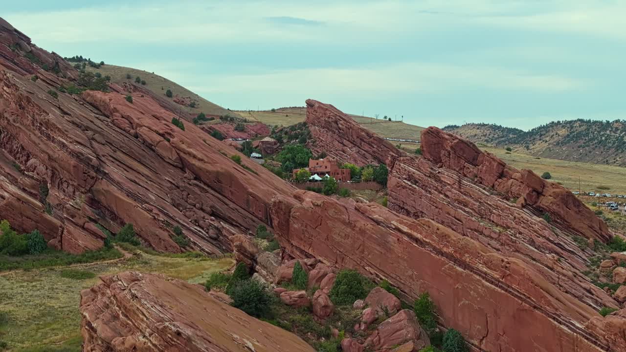 Drone ascend over natural amphitheatre and towering red rock cliffs near Denver Colorado, wide aerial perspective