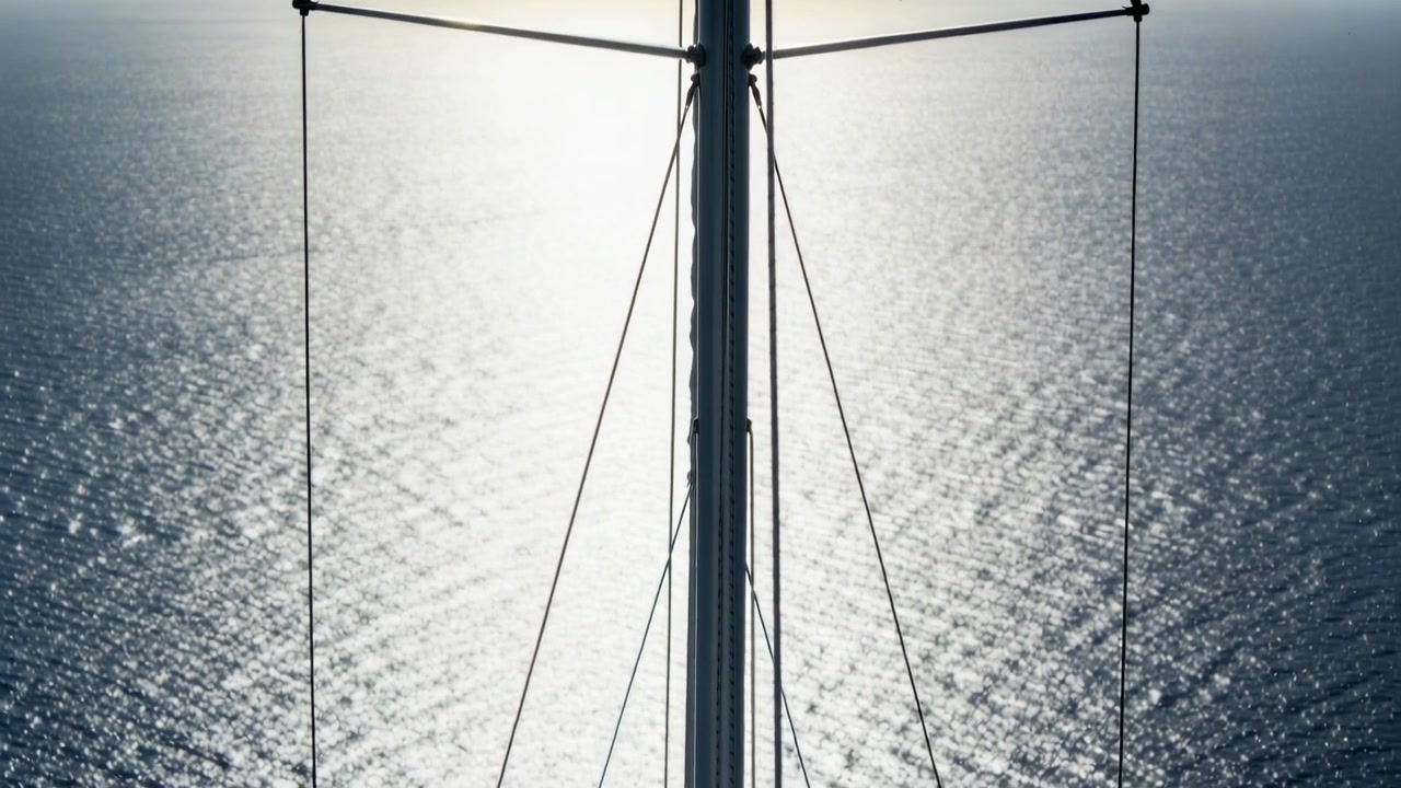 Bewegte Kamera nähert sich Segelbootmast, enthüllt Salinge, Takelage und Beschläge auf offenem Meer.