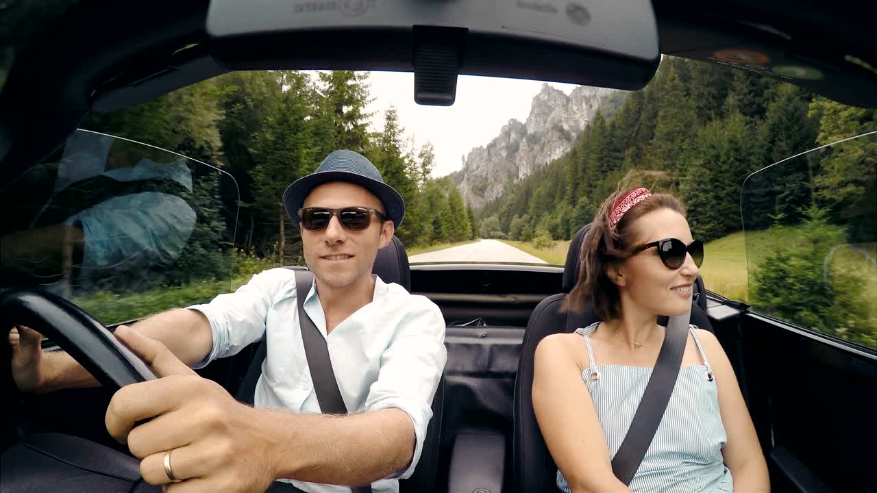 imágenes de 4k de una pareja viajando en un coche sin tapa: una mujer cantando