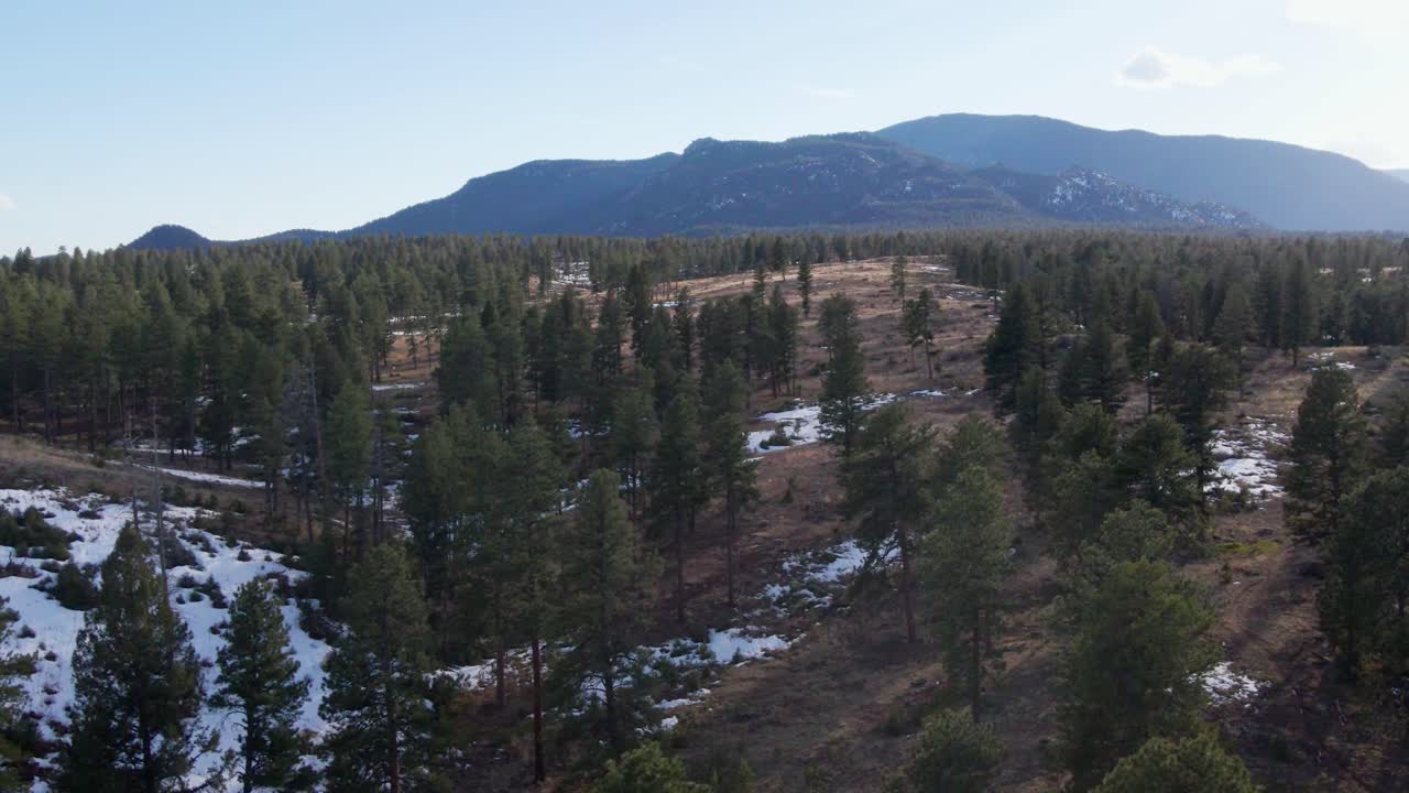 Aerial drone view of the Pike National Forest and Little Scraggy Mountain and Green Mountain. Forward dolly movement with sun flare. Filmed in the Rocky Mountains of Colorado.