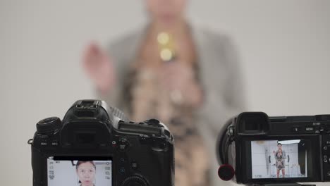 before recording a television program, a woman does a sound check with the microphone - focus on cameras in the foreground