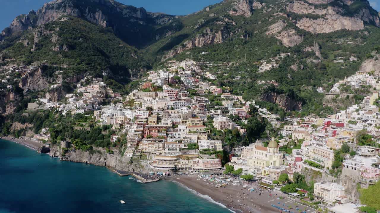 Vista aerea del villaggio di Positano sulla costiera amalfitana in Italia. Ripresa orbitante di un drone sopra il famoso resort sul lungomare mediterraneo con acqua di mare turchese