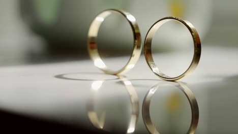 close-up of golden wedding rings arranged on the surface of a glass table