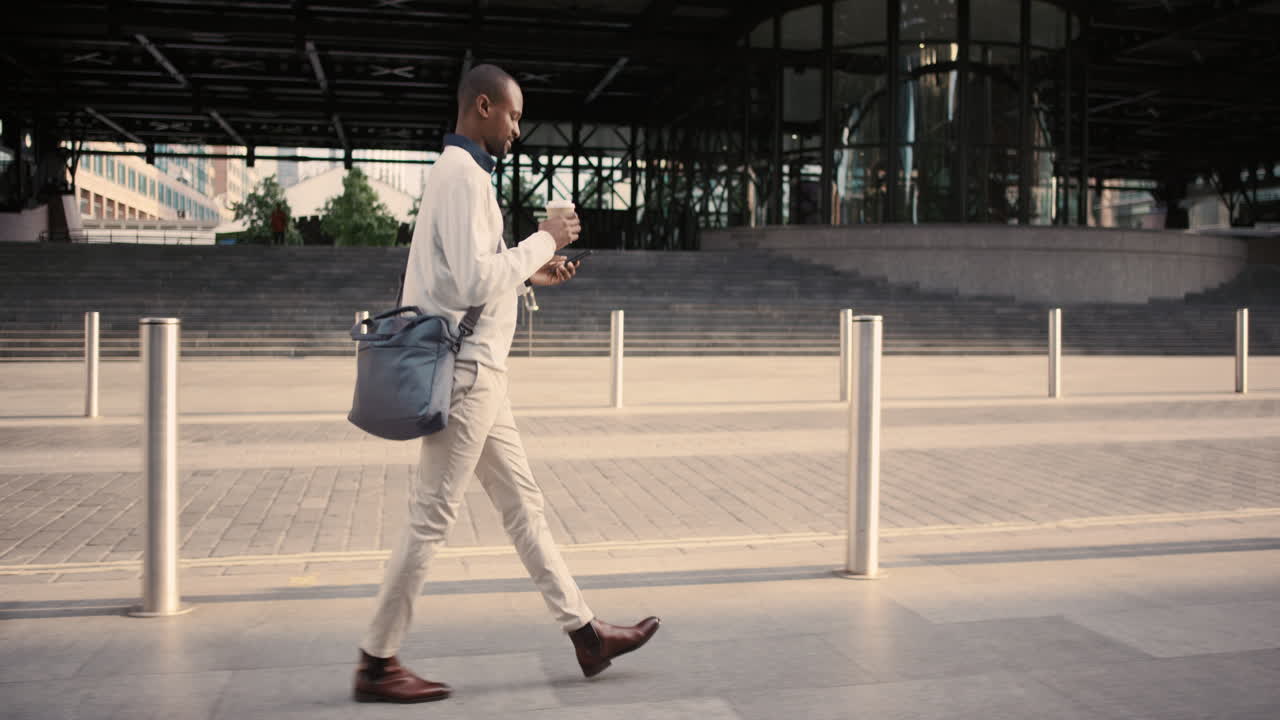 African American businessman walking through city using smart phone