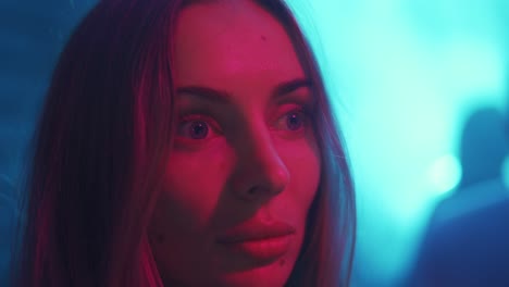 Cinematic-close-up-portrait-of-stylish-woman-in-neon-lighted-interior,-cinema-effects-in-purple-blue