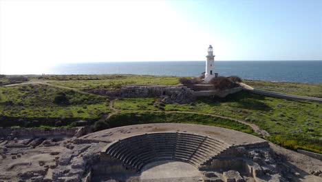 Beautiful-drone-footage-flying-over-an-ancient-Greek-Odeon-and-towards-a-white-lighthouse-on-the-shores-or-Greece