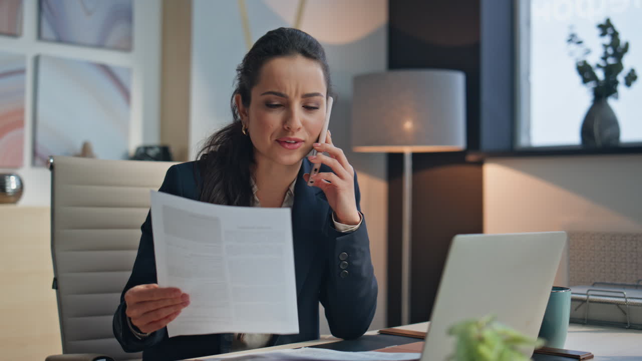 Happy manager calling smartphone looking papers office. Smiling woman speaking