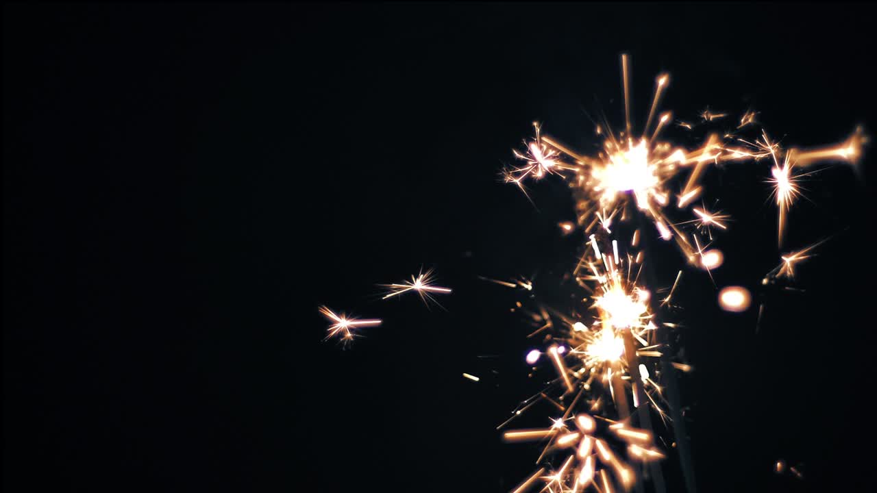 Fuoco del Bengala su sfondo nero, scintille luminose di stelle filanti in festa. Filmato stock.