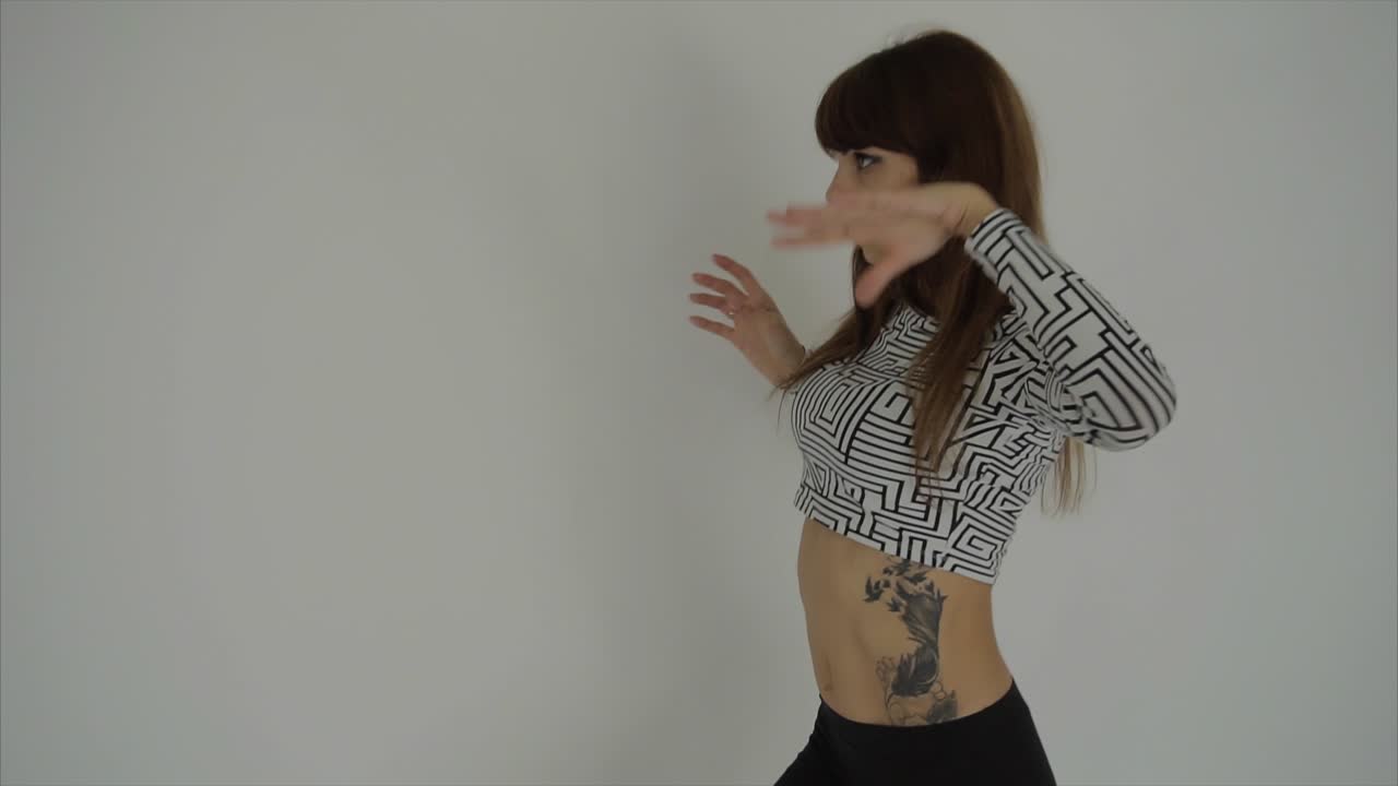 женщина танцует в стильном кроп-топе и леггинсах.