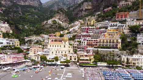 Imágenes-Aéreas-De-Drones-Establecen-La-Escena-De-La-Playa-Marina-Grande,-Iglesia-De-Santa-Maria-Assunta-En-Positano,-Costa-De-Amalfi,-Campania,-Italia