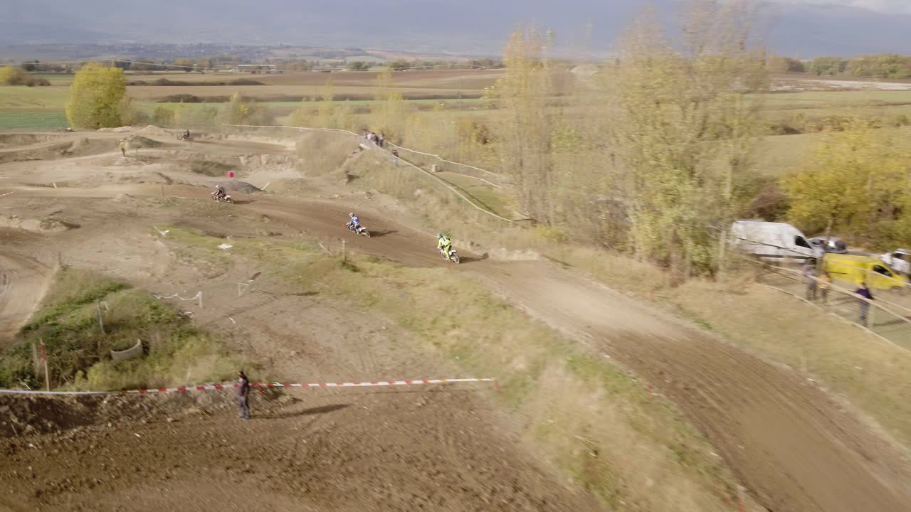 toma aérea siguiendo a los pilotos de motocross en la pista de carreras