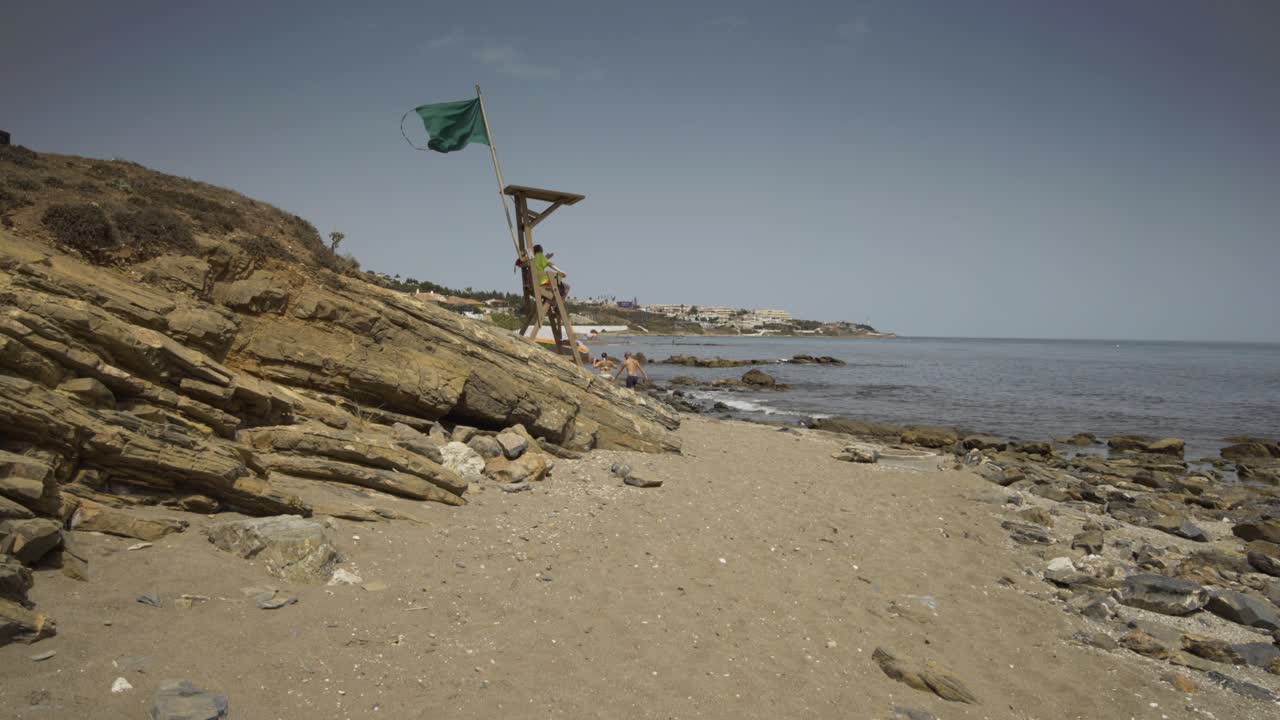 Walking along from La Cala de Mijas beach toward lifeguard station on hot sunny day