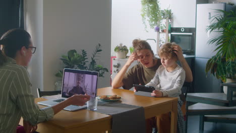 woman having video call on laptop while wife sitting with child