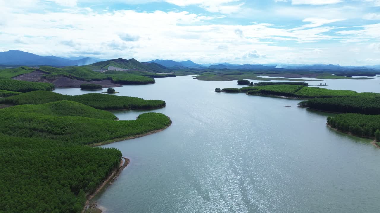 Cinematic drone zoom out showing Vietnam lake and lush islets under blue sky and scattered clouds