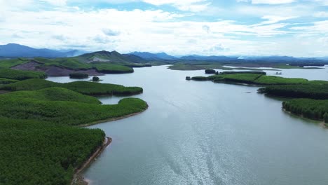 cinematic drone zoom out showing vietnam lake and lush islets under blue sky and scattered clouds