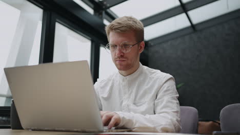 adult-handsome-man-is-surfing-internet-in-office-or-coworking-space-looking-for-info-and-reading-news