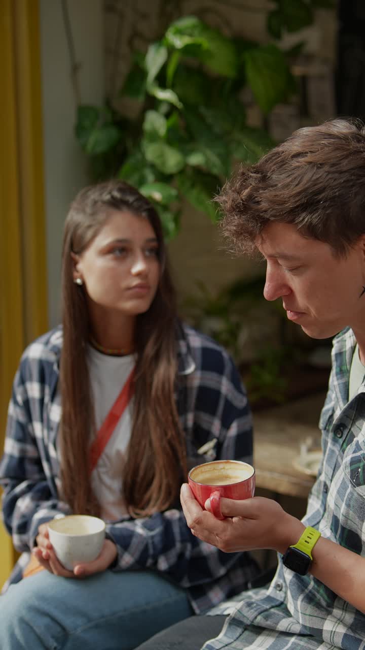 una pareja disfrutando de café y teléfono en un café