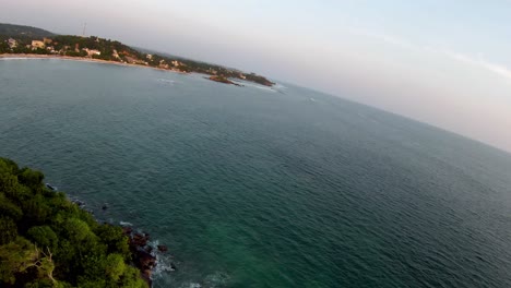 drones aéreos se desplazan sobre la ladera de la isla con árboles hasta el océano azul profundo al atardecer en sri lanka