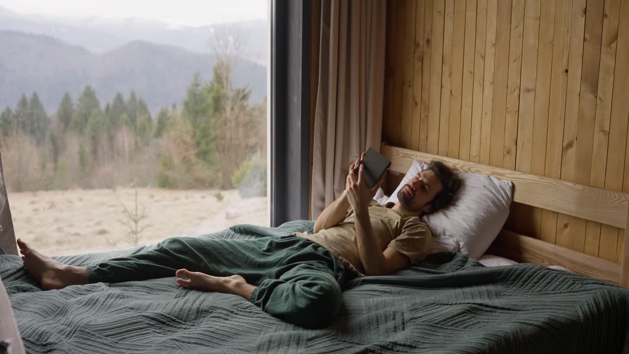 Man relaxing in bed with a tablet in a cabin