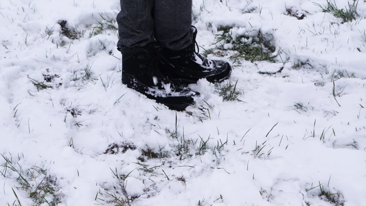 Toma a cámara lenta de una persona lanzando una bola de nieve con botas en un paisaje invernal blanco