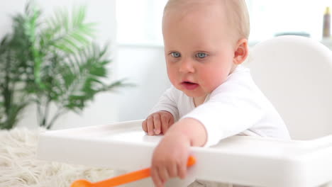 bebé sentado y jugando con cuchara de naranja